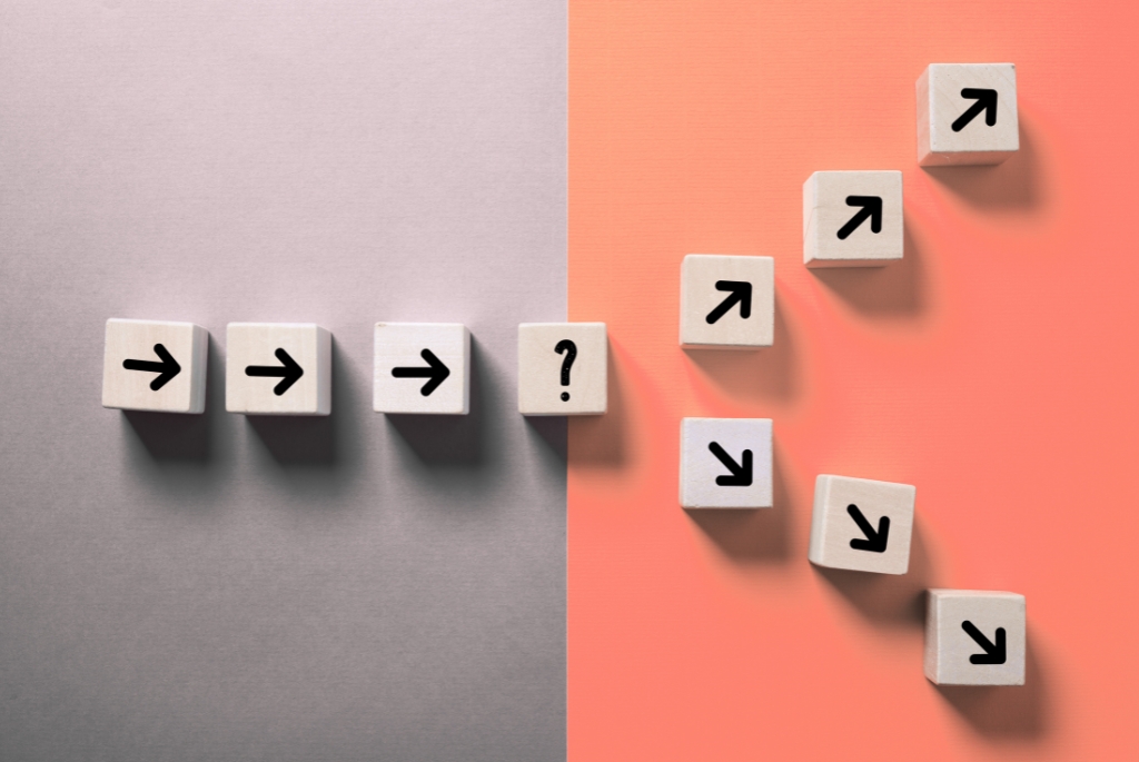 Wood blocks with arrows in a line splitting into two paths of contract vs full time employee