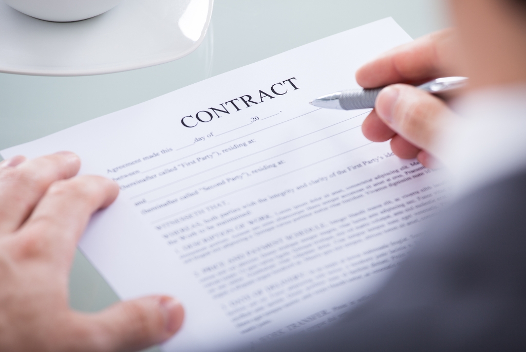 Hand and pen hovering over contract document for best contract jobs