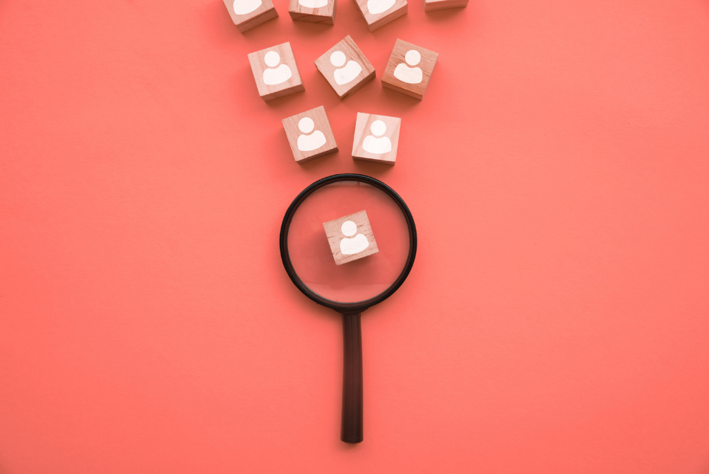 Magnifying glass hovering over wood block with person on it